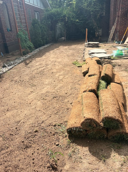 Graded soil prepped with rolls of fresh sod ready for install