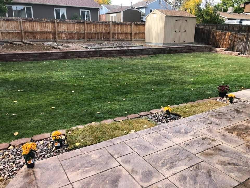 Finished backyard with new sod, stone border and stamped concrete patio